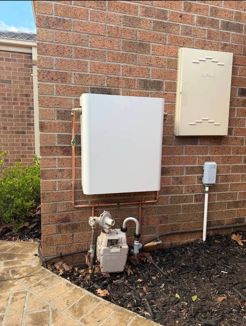 Whole House Filtration unit in Surfmist on a brick wall beside the gas meter